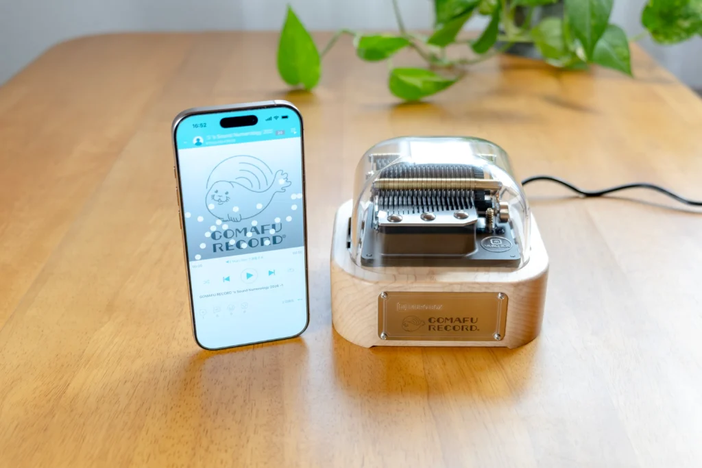 Muro Box というオルゴールとそのアプリをiPhone で見せている画像